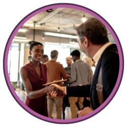 Woman shaking hands with a man with groups of people in the background