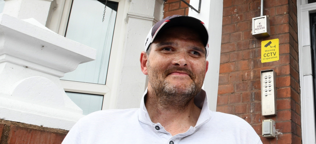 Stephen - former rough sleeper appears outside a home of his own.
