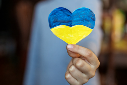 Heart shaped Ukraine flag being held up in front of someone.