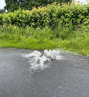 Blocked gully on roadside and water overflowing onto road